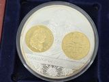 two gold and silver coins in a velvet case on a red surface