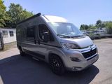 a silver motorhome parked in a parking lot next to a building