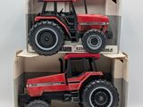 two red toy tractors in a cardboard box on a white surface