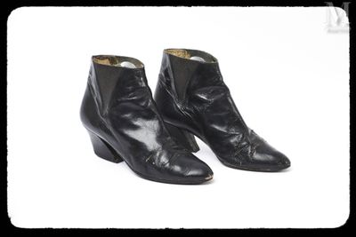 une paire de bottines en cuir noir sur fond blanc