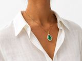 a woman wearing a white shirt and a green necklace