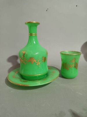 a green vase and a cup sitting on a table