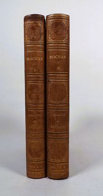 two old books sitting on top of each other on a white surface
