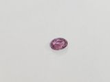 a pink sapphire stone on a white surface
