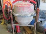 a cement mixer sitting in a garage with other tools