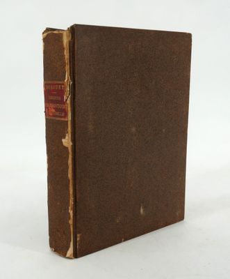un vieux livre à la couverture brune posé sur une surface blanche