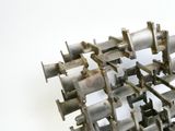 une sculpture métallique composée d’éléments métalliques posés sur une surface blanche