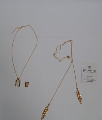 deux colliers en or et un collier orné d'une plume sur fond blanc