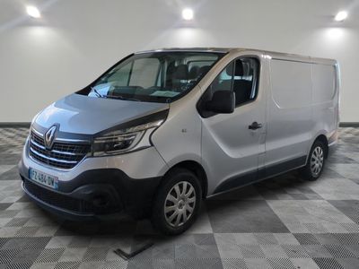 La camionnette argentée est garée sur un sol à damier dans un garage.