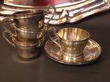a silver cup and saucer sitting on a table next to a silver tray
