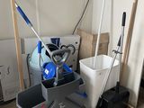 a mop, bucket, broom and bucket on the floor in a room