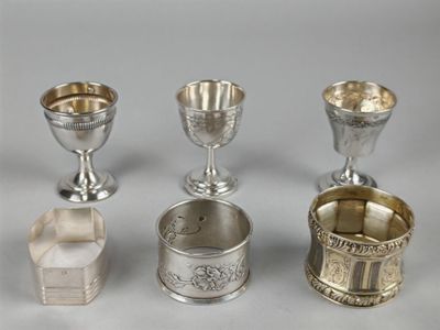 several silver cups and spoons sitting on a table next to each other