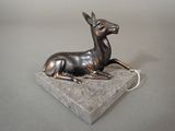 statue of a deer on a stone base on a gray surface