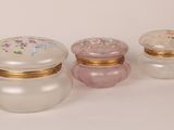 three small glass containers with gold trims and flowers on them