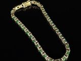an emerald and diamond bracelet on a black background