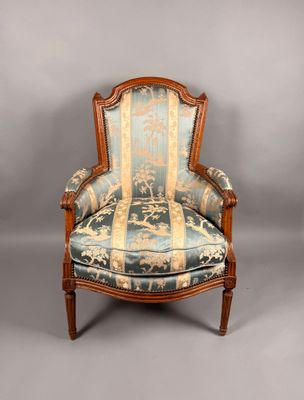 une vieille chaise dont l'assise est recouverte d'un tissu bleu et or