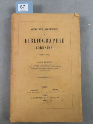 un vieux livre posé sur une table, à côté d'une étiquette bleue
