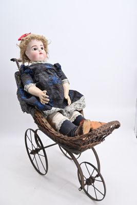 une petite poupée assise dans un landau en osier