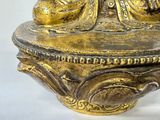 a gold statue of a person sitting on top of a bowl