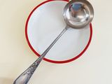 a silver spoon sitting on a red and white plate next to a silver spoon