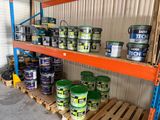 Plusieurs pots de peinture sont empilés sur des palettes dans un entrepôt