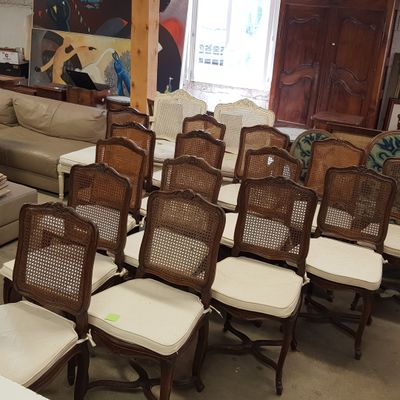 de nombreuses chaises et canapés dans une pièce où est accroché un tableau au mur