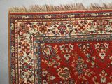 une photo d'un tapis rouge orné d'un motif floral et de franges