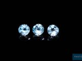 three blue topaz gems on a black background