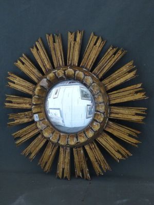 un miroir doré en forme d'étoile sur le mur, à côté d'un mur noir