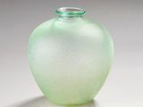 un vase en verre vert posé sur une surface blanche
