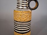 a black and white striped vase with a brown handle