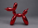 a red balloon dog sculpture sitting on top of a gray surface