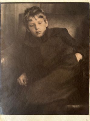 an old black and white photo of a young boy sitting in a chair
