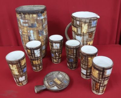 sept tasses et un pichet posés sur une table rouge
