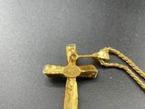 a gold cross with a rope on a black surface