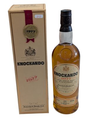 a bottle of knockandoo whisky next to a cardboard box