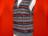 knitted vest on a mannequin stand against a red background