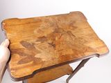 a person holding a small wooden table with a leaf design on it
