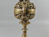 a brass vase on a stand on a white background