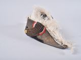 a small hat with a feather on it on a white surface