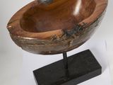 a wooden bowl sitting on a stand on a white surface