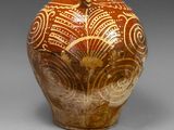 un vase marron orné de motifs sur un fond gris