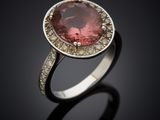 a close up of a ring with a pink stone surrounded by diamonds