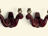 pair of red wall sconces with brass fittings on each of them