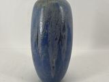 un vase bleu posé sur une surface blanche