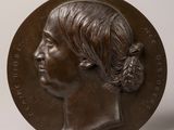 two bronze medallions of a woman with a ponytail and a man ' s face