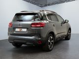 the rear end of a grey car parked in a garage