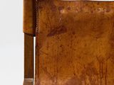 an old brown leather chair with a wooden arm rest