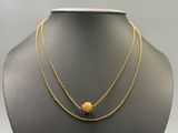 a gold necklace with a ball and chain on a mannequin
