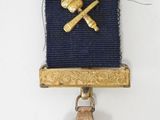 une image représentant un petit insigne orné d'un marteau et d'une cloche